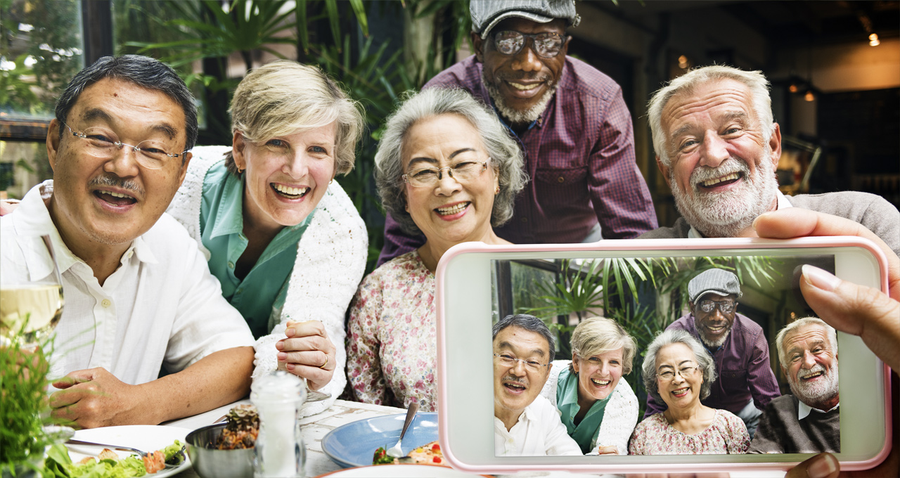 A group of older people smiling and taking selfies. 