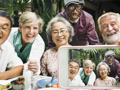 A group of older people smiling and taking selfies. 